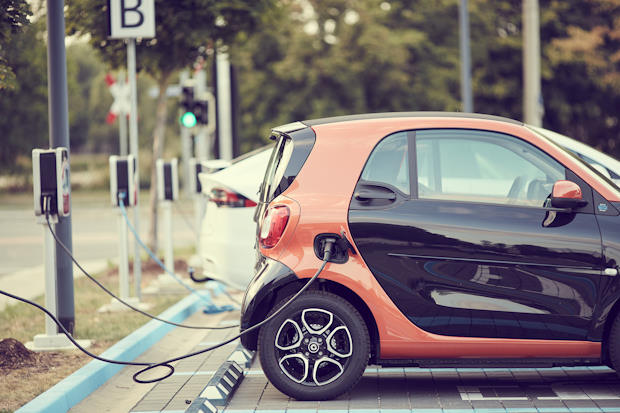 Kleine elektrische auto aan de lader.