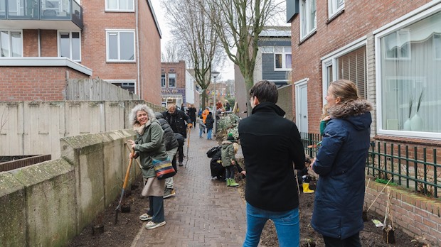 Inwoners planten groen langs gevel van huizen.