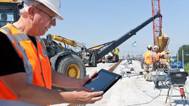 Bouwplaats waar medewerker met tablet werkt aan digitale processen en AI in de bouw calculatie
